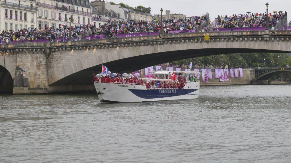 Athletes sail in a boat along the River Seine as rain starts at the beginning of the opening ceremony of the Paris 2024 Olympic Games