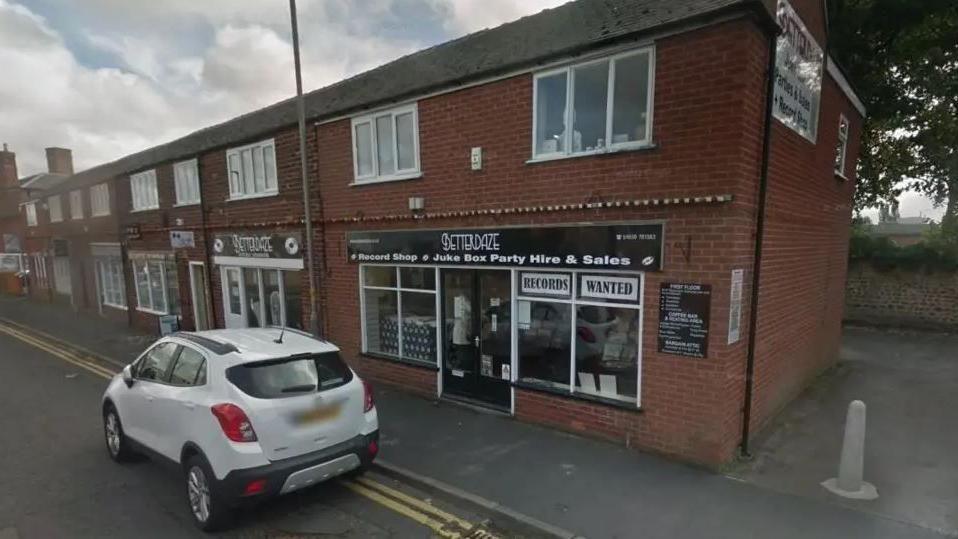 The Betterdaze record shop in Northallerton, a red brick two storey building with a black and white sign and a white car outside 