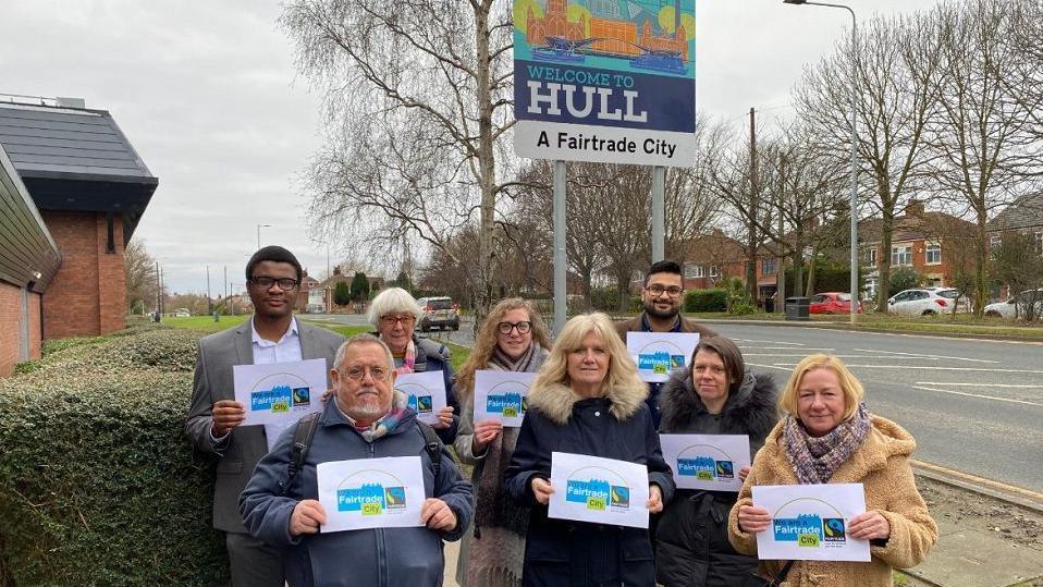 Stood in front of the new Fairtrade sign at the Bilton boundary from L-R are Ejimchi Peter-Dumbili, Peter and Chris Church, Lauren Murtagh, Julia Conner, Gurmok Sanghera, Ruth Cowlam and Sharon Clay.