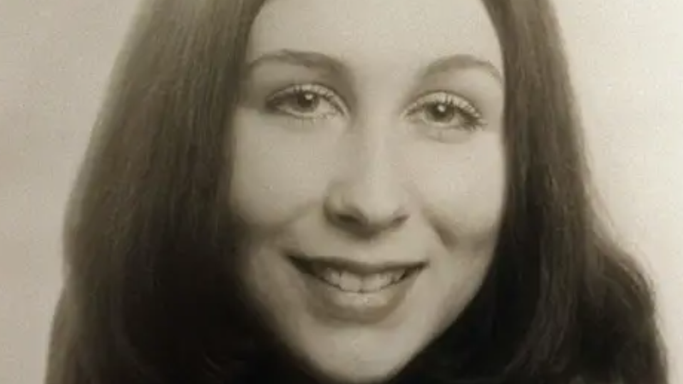 Black and white headshot of a woman with long hair smiling at the camera.