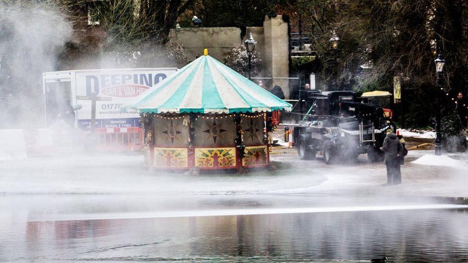 A fairground stall can be seen next to St Albans' Verulamium lake as fake snow is sprayed around. 