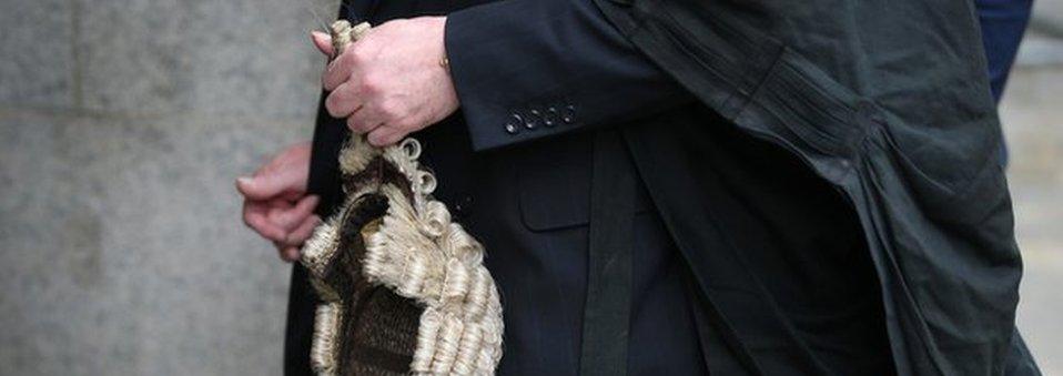 A barrister holds his wig as he arrives at The Old Bailey on 27 July 2015