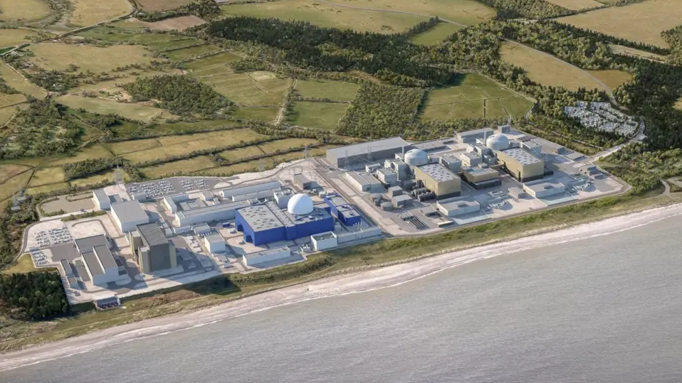 An aerial shot of what Sizewell C will look like once built. It is on the coast with green fields and woodland behind it. 