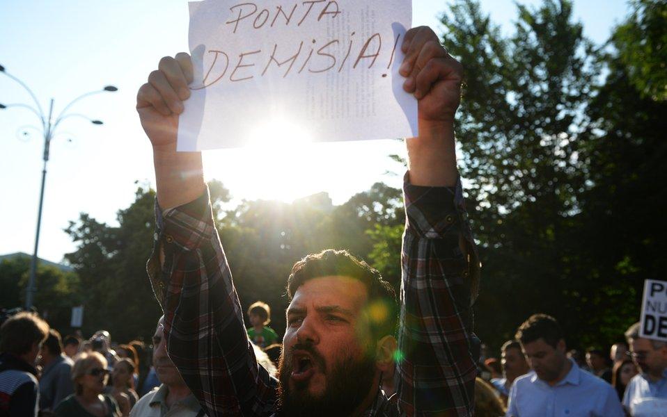 A man holds a placard reading in Romanian 'Ponta, RESIGN!' during a protest asking the resignation of Romanian Mr Ponta next to Romanian Government headquarters in Bucharest on June 5, 2015.