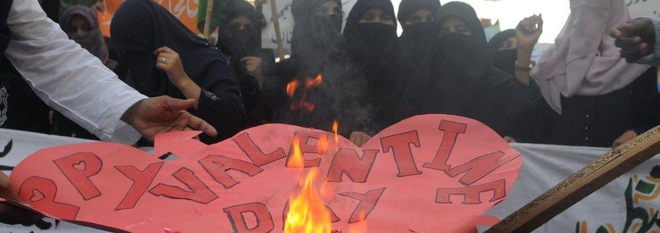 Pakistani women belonging to religious party Jamiat-e-Ulama Pakistan set fire to Valentine's Day cards during a protest against valentine's day in Karachi on February 14, 2012