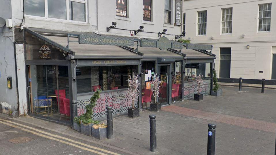 Streetview of the Wafi Lounge, it is a grey building with a glass conservatory-style section wrapping around the building.