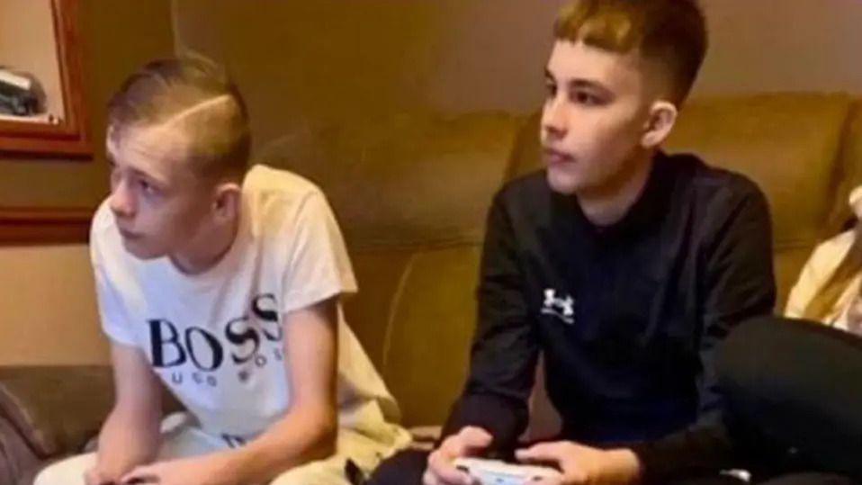 Max and Mason sitting on a sofa playing video games. They are looking into the distance, to the left, concentrating on a fixed spot.