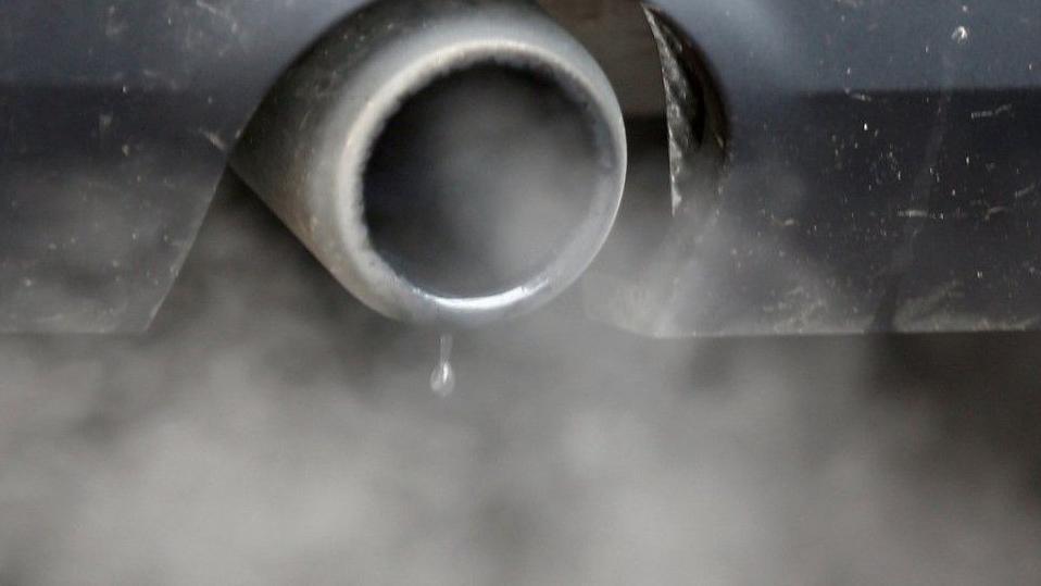 A close up image of fumes pouring out of the exhaust pipe of a vehicle