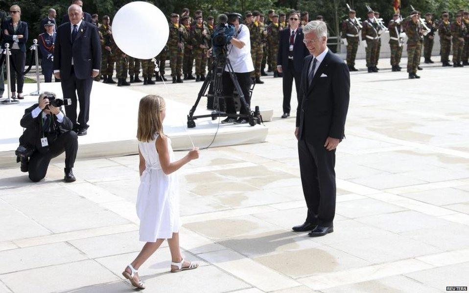 King Philippe of Belgium is handed a balloon by a girl dressed in white in Liege