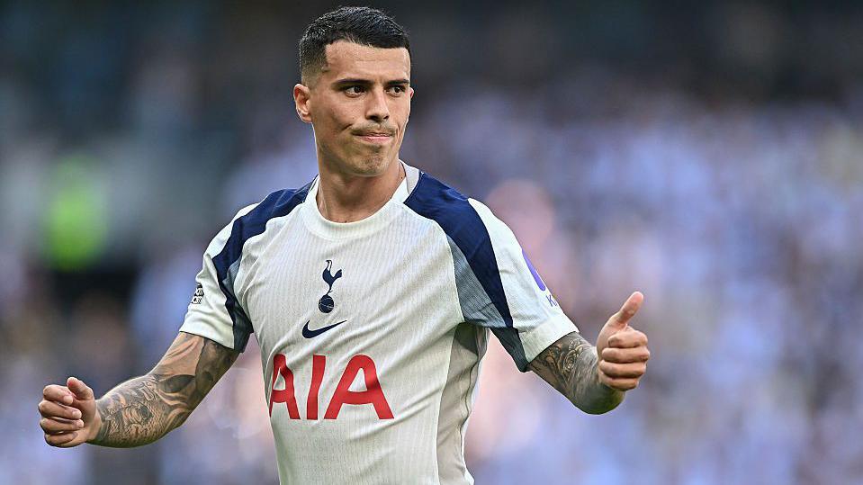 Pedro Porro, wearing a white Tottenham shirt, gives a thumbs up