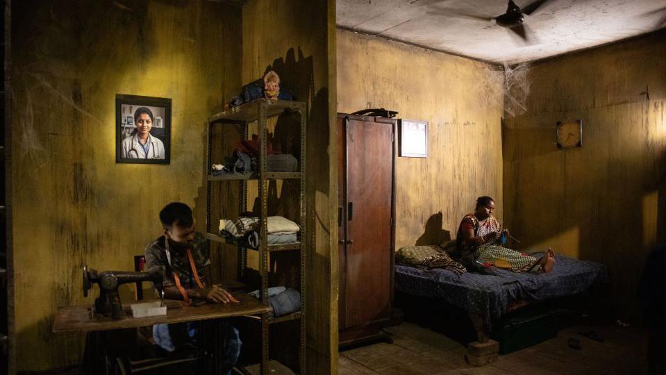 A tableau recreates the bereaved family of the doctor whose portrait hangs on the wall at a Puja