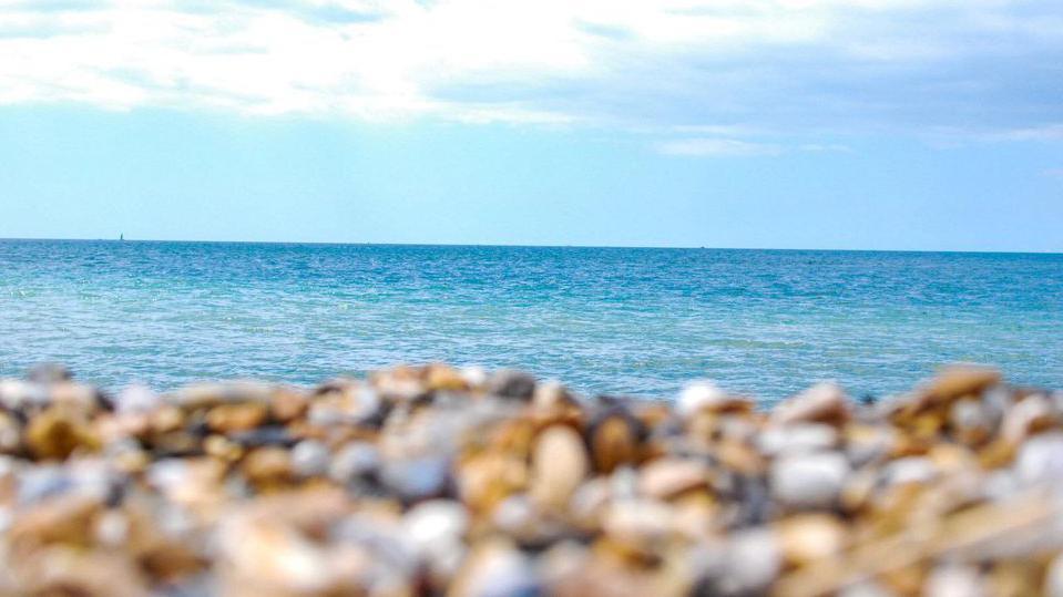 Blurred pebbles on the shore in front of the sea 