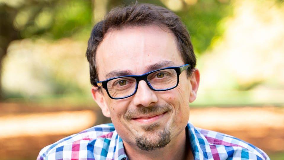 A close-up of a man wearing glasses and a red, white and blue shirt.