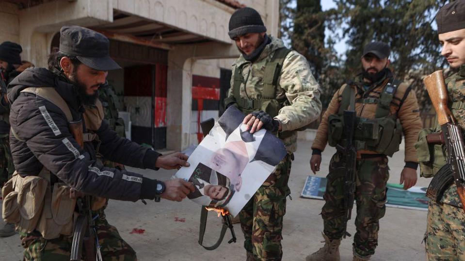 Fighters set alight a picture of Syrian President Bashar al-Assad in front of a building that was seized by jihadists in the area of Zarbah on November 29, 2024,