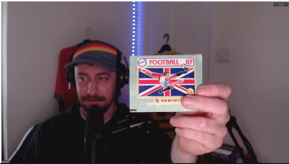 Ollie Jenks holding up an opening pack of 1987 Panini football stickers