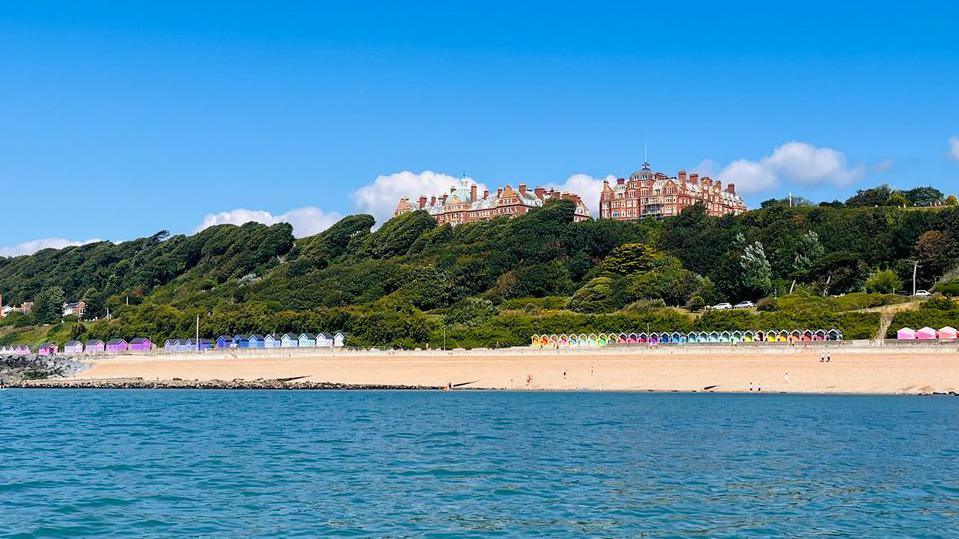 The sea in front of a beach. And a big building in the distance. 