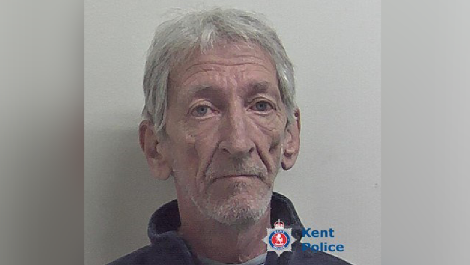 Mug shot of elderly man with grey hair and  stubble. 