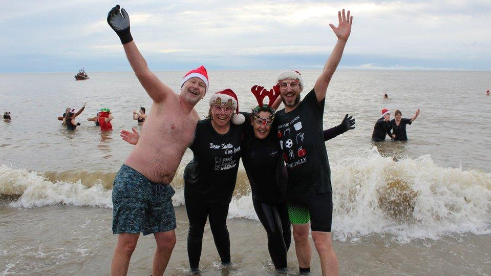 Two men and two woman standing in the sea while laughing and smiling