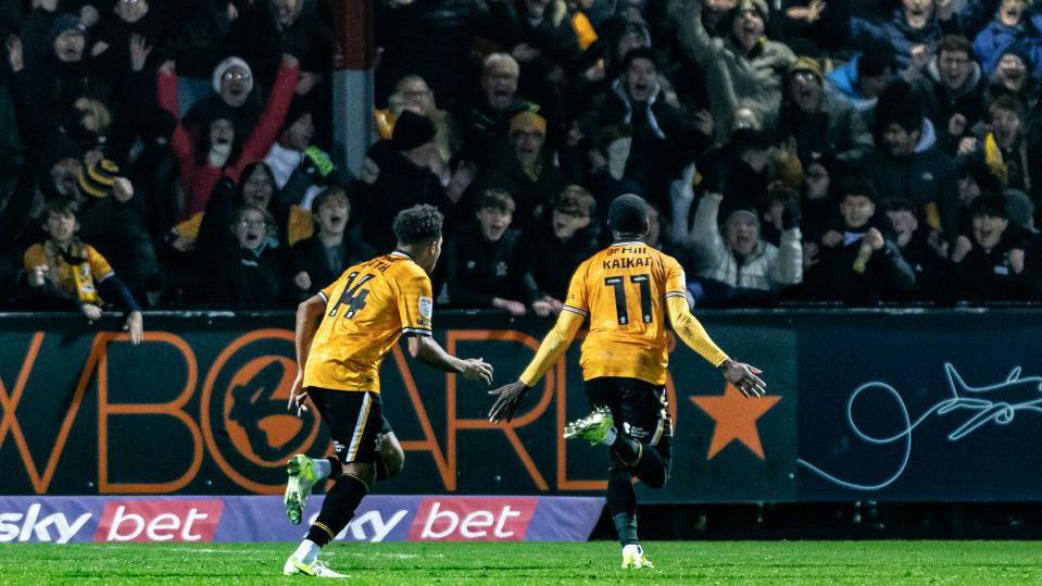 Sullay Kaikai runs towards a jubilant set of Cambridge fans after scoring against Bolton