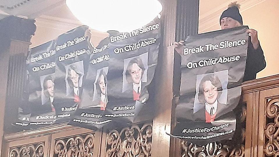 Protesters on a balcony at Blackpool Town Hall holding black banners which say Break the Silence on Child Abuse with a picture of Charlene Downes underneath.