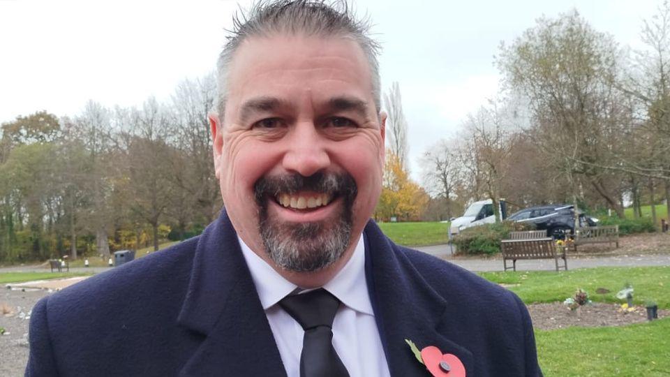 Head and shoulders picture of Jonathan Tinning smiling in the crematorium grounds