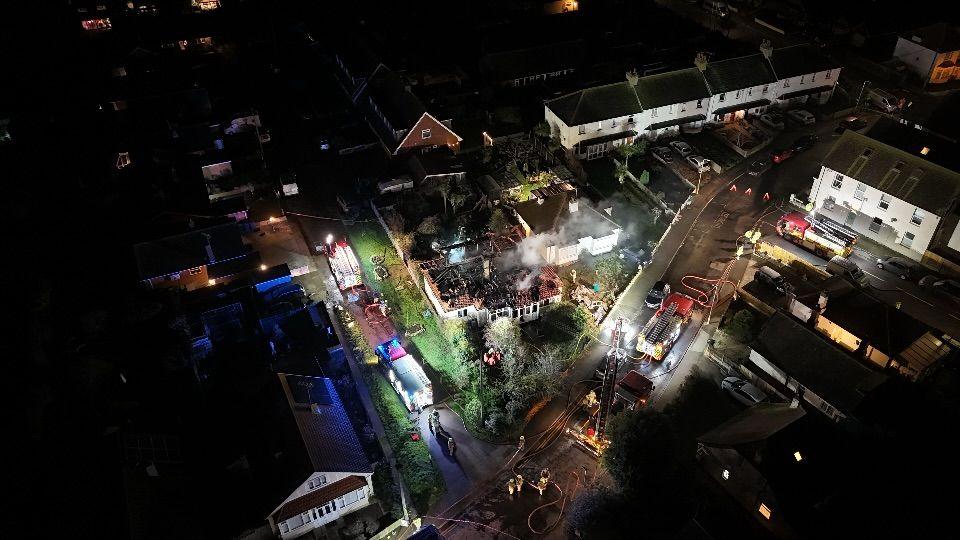 An aerial view of the house fire in Grand Drive with fire engines in the street and smoke coming from the burnt out house