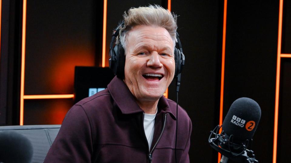 Gordon Ramsay sits in front of a Radio 2 microphone smiling while looking at the camera