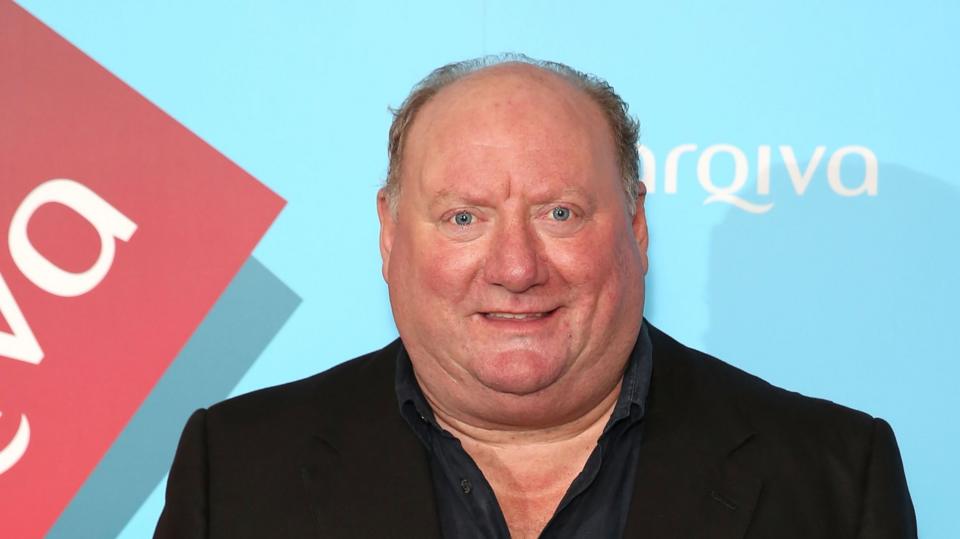A picture of Alan Brazil wearing a blazer and shirt.