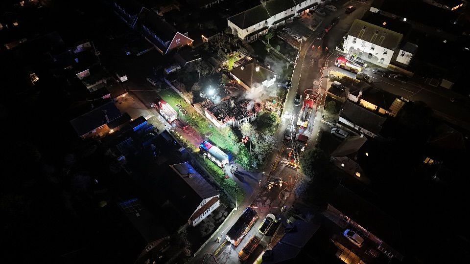 An aerial view of the house fire in Grand Drive with fire engines in the street and smoke coming from the burnt out house