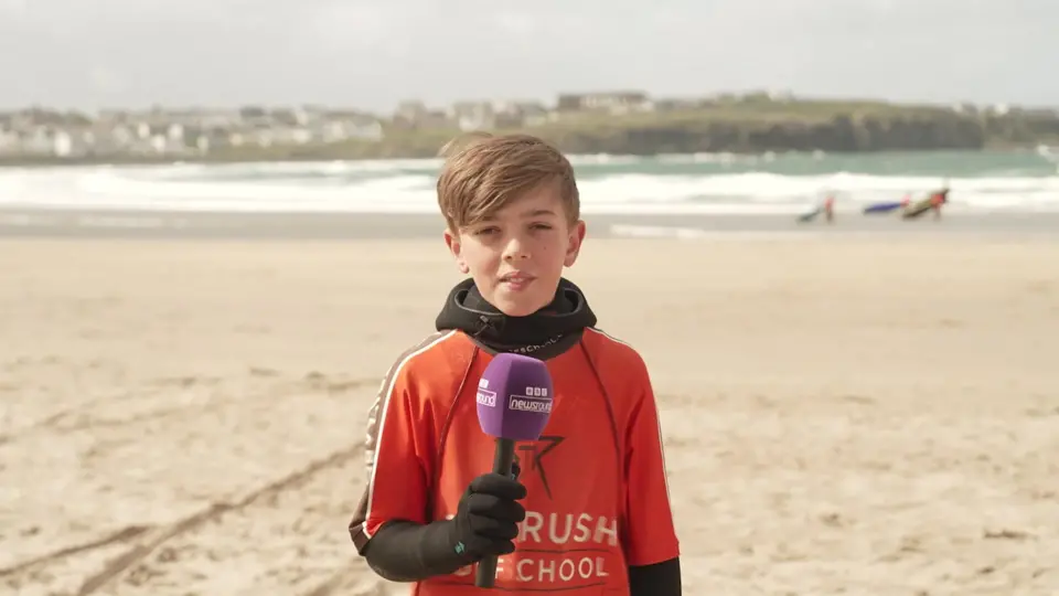 Child Max looking at camera stood on a beach.