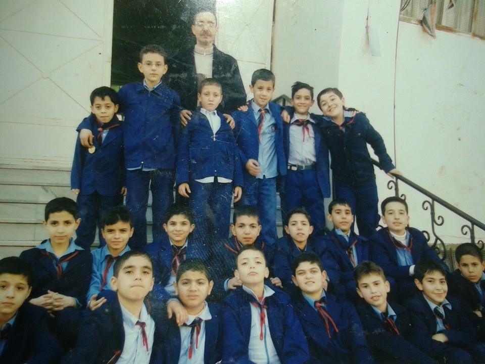 Saad with his Grade 6 teacher and classmates in Homs, Syria, before the war forced schools to close