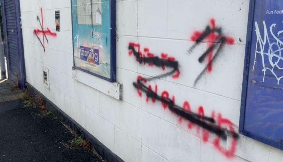 A large white wall bears the message in red spray paint this is England. There is also a cross of St George alongside it, again using red spray paint. Each marking has been crossed out in black spray paint.