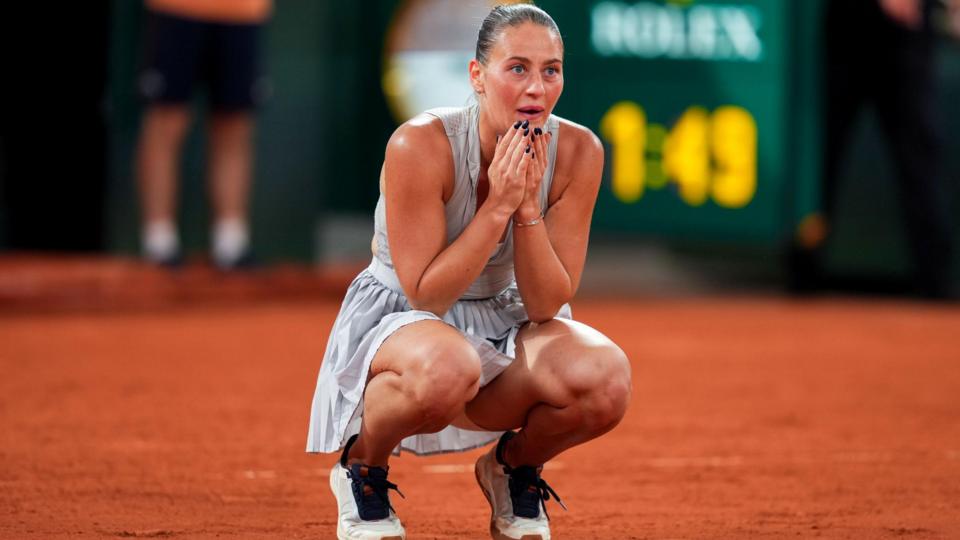 Marta Kostyuk crouches down with her hands on her face after completing victory over Elina Svitolina