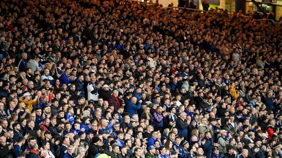 Crows of football fans clapping their hands during a tribute