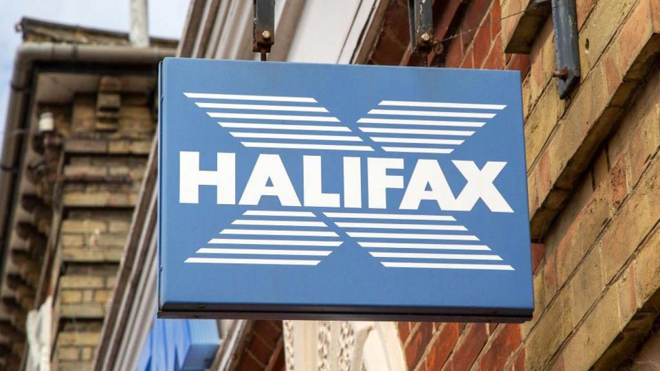 Close-up image of a Halifax sign in blue and white, hanging off a traditional high street building.