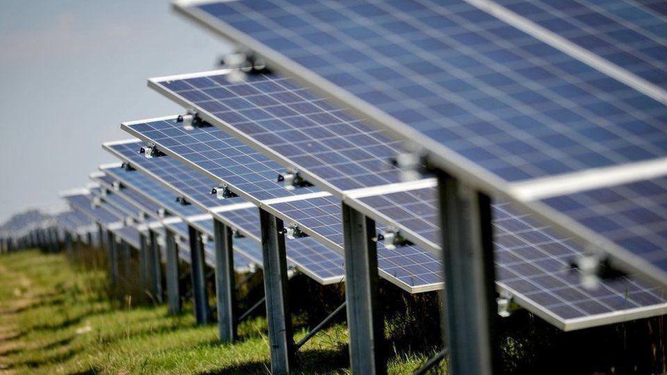 A row of solar panels seen from close-up in a grass field