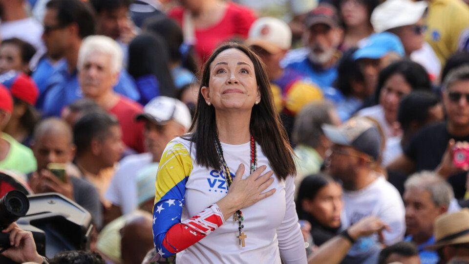 María Coria Machado holds one hand to her chest, as a crowd stands behind her