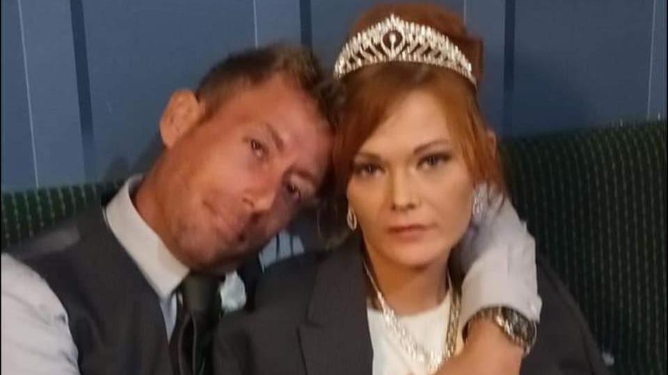 A man and woman on their wedding day look at the camera