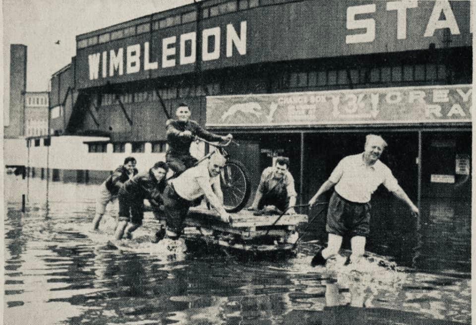 Ronnie Greene, the stadium promoter pulls a trolley through flood waters, Cyril Brine is mounted on the speedway bike