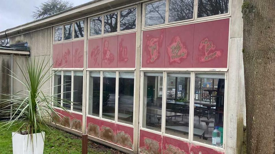 The outside of Templewood Primary School in Welwyn Garden City shows metal framed windows and peeling paint panels