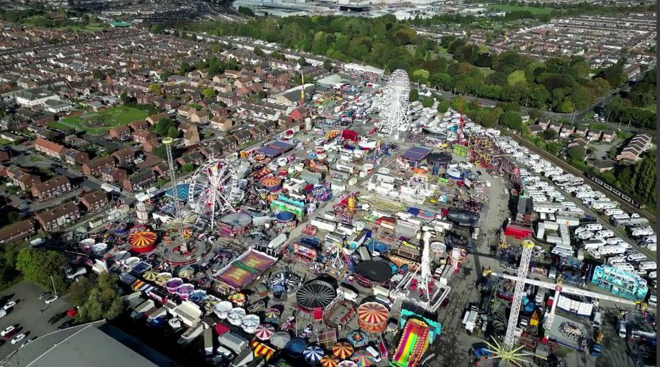 An aerial view of Hull Fair showing houses bordering on the left hand side of the site and a line of caravans and on the right hand side. 