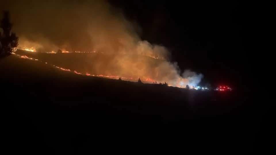 Wildfire going across the land in a line in a night-time shot