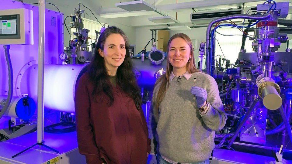 two scientists in front of the technology used to make the violin