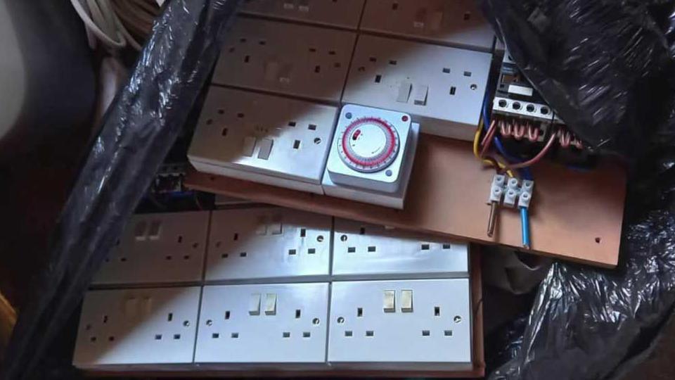 A black plastic bin bag filled with double plug sockets.