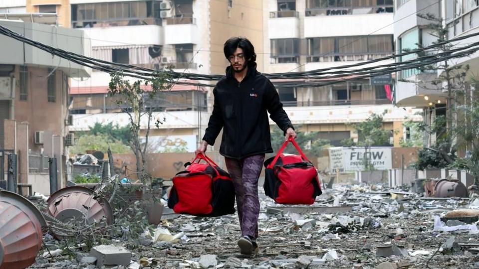 A Lebanese man carries his belongings as he leaves following an Israeli air strike 