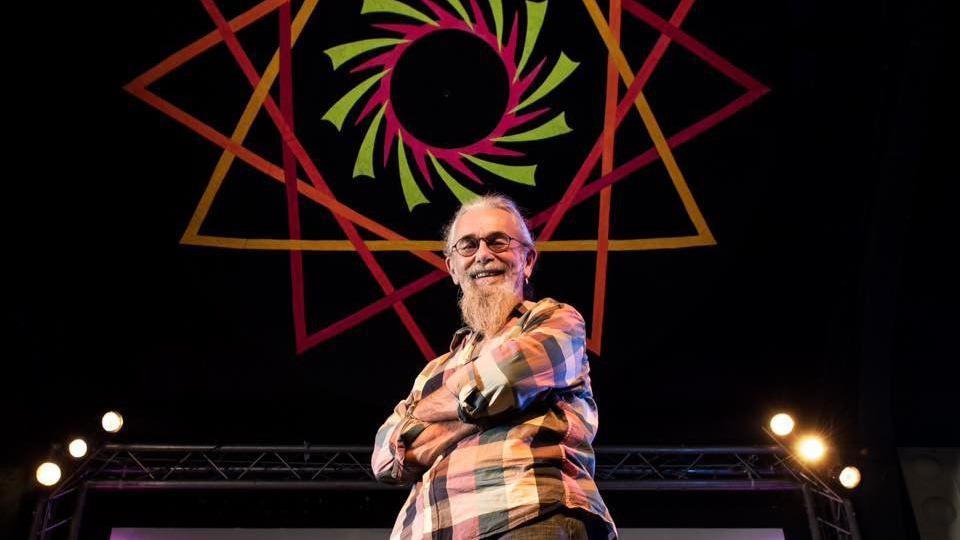 Bob Marden smiling on stage with his hands folded 