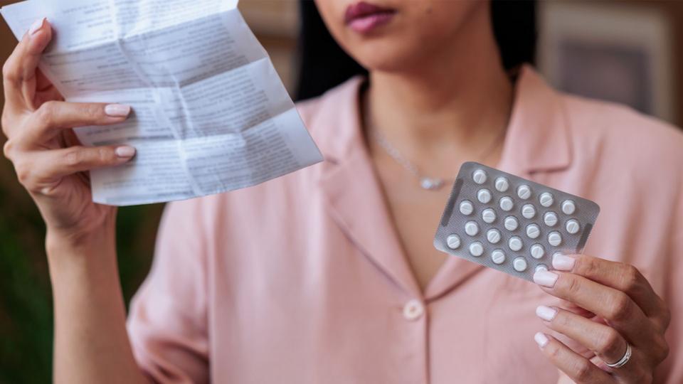 Woman eating instructions leaflet before taking medication