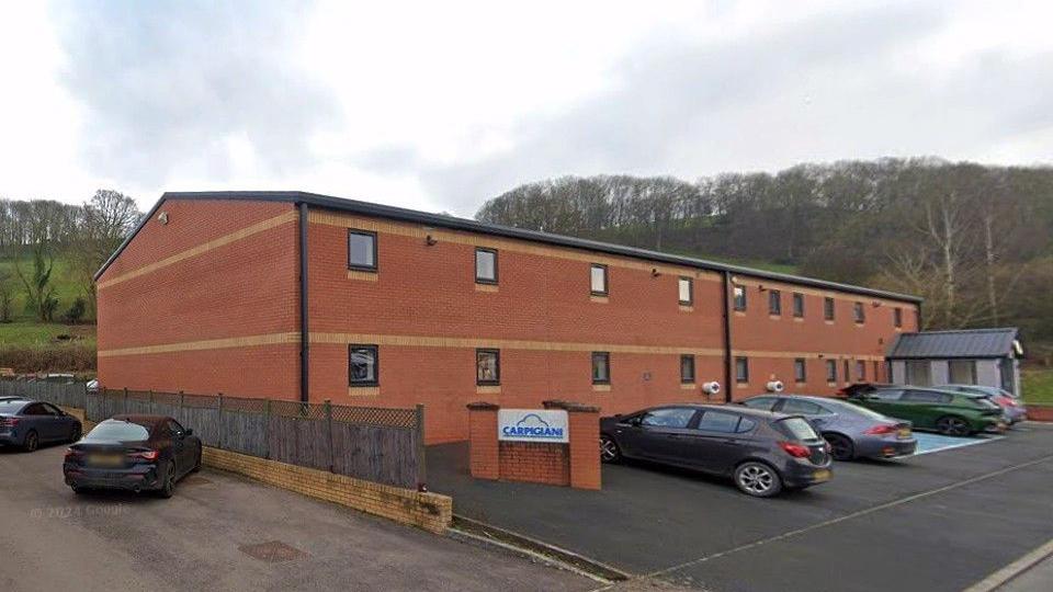 Red-brick office building with cars parked outside