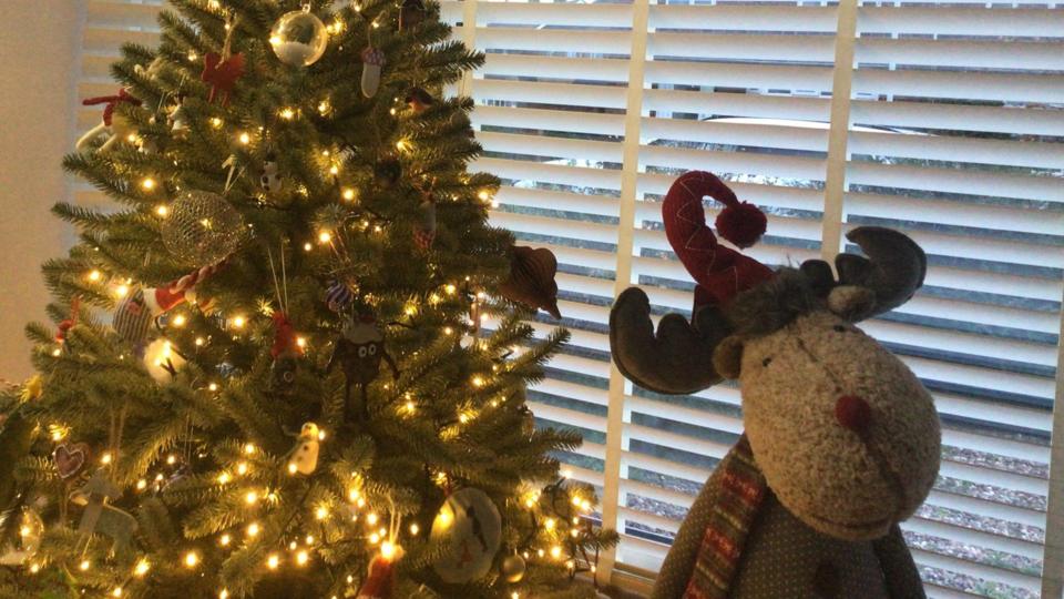 A photo of some Christmas tree decorations with a knitted reindeer next to it.
