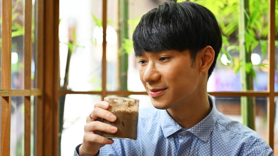 Young man holds a glass of hojicha.